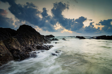 Fototapeta na wymiar beautiful sunrise background,waves splashing on the unique rocks