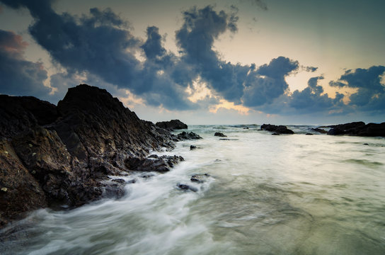 beautiful sunrise background,waves splashing on the unique rocks © amirul syaidi