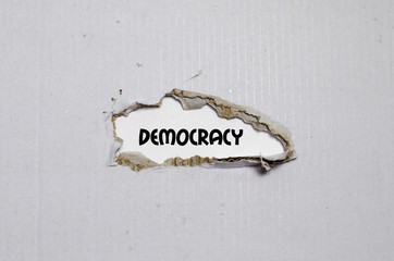 The word democracy appearing behind torn paper