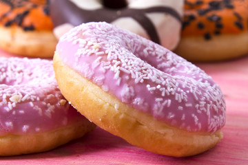 collection of colorful donuts on wooden pink