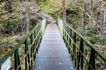 Diminishing perspective of metal suspension footbridge over rive