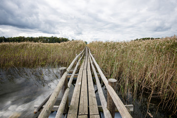 Obraz premium Diminishing perspective of wooden suspension footbridge over riv