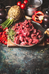 Raw Beef goulash of young bulls with vegetables and cooking ingredients on dark rustic background ,...