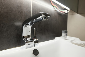 chrome water tab and seramic sink bowl in bathroom. selective fo