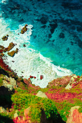 Sea turquoise water hitting rocks of steep cliff