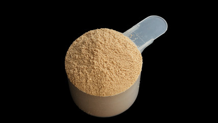 Whey protein powder scoop on a black background.