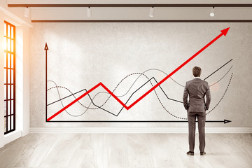 Man in brown suit is looking at graphs