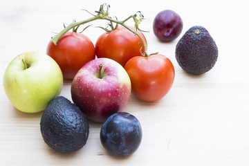 Autumn mood with apples, plums, tomatoes, avocados on a wooden background