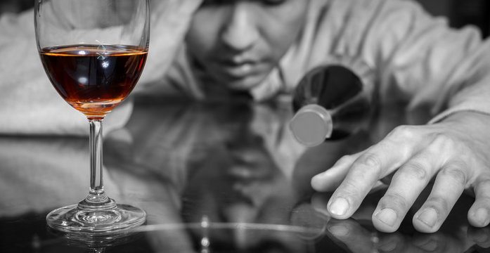 drunk, lonely asian man with wine glass and whiskey bottle. focus on glass