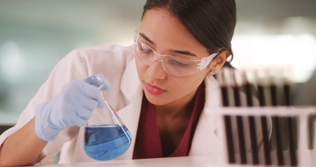 Hispanic scientist looking at liquids in vials