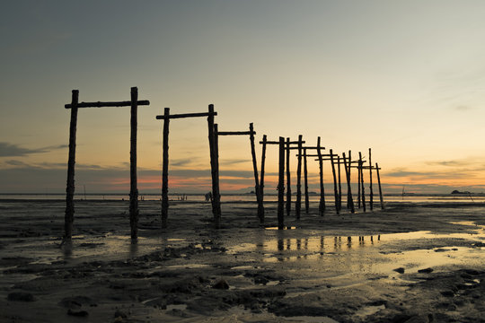 Golden Hour moment,beautiful tropical sunset background, wooden water pump tower on the muddy beach. cloudy and yellow sky.surface level shot.low tide sea view