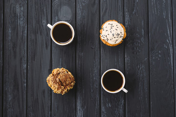 homemade muffins and two cups of cofee on black wooden background