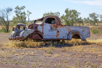 Old rusty abandoned car in outback Australia with town in background