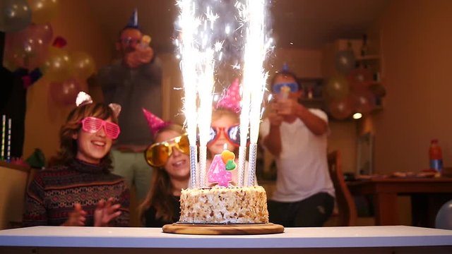 Cheering people birthday party - firework candles burning on a cake and colorful streamers confetti flying around