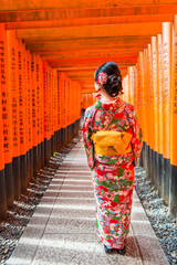 Women in kimono stand at Red Torii gates in Fushimi Inari shrine, one of famous landmarks in Kyoto,...