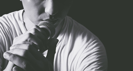 emotion portrait of asian male singer holding microphone, bw filter & isolated on black