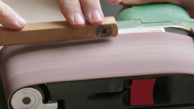 Belt sander, close-up / Process of grinding the wooden piece on the belt sander