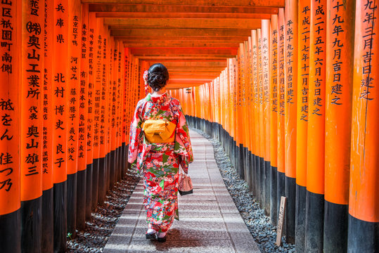 Women in kimono stand at Red Torii gates in Fushimi Inari shrine, one of famous landmarks in Kyoto, Japan