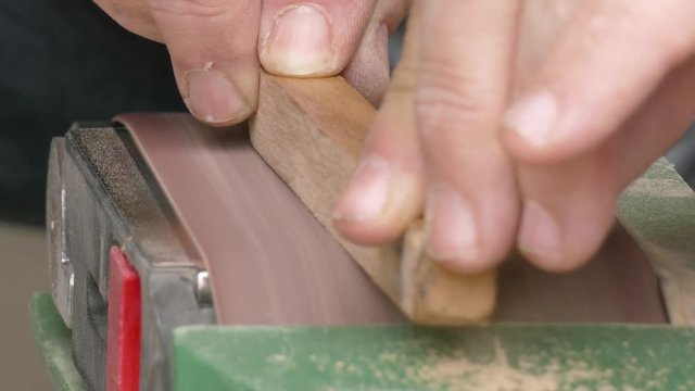 Belt sander / Process of grinding the wooden piece on the belt sander, close-up