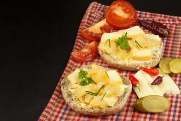 Two kinds of cheese on bread. Healthy breakfast on the kitchen table. Bread with cheese cherry tomato and chilli. 
