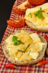 Two kinds of cheese on bread. Healthy breakfast on the kitchen table. Bread with cheese cherry tomato and chilli. 
