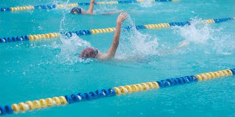 Competitive swimming with events in backstroke. Boys are swimming in a race. Focus on water splash,...