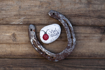 Hufeisen Silvester Glücksbringer mit Hufeisen, Marienkäfer und Kleeblatt auf Holzhintergrund