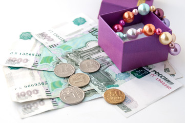 Pearl necklace in gift box stands on thousandths bills and coins