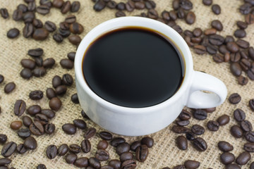 White cup with coffee drink on jute bag background