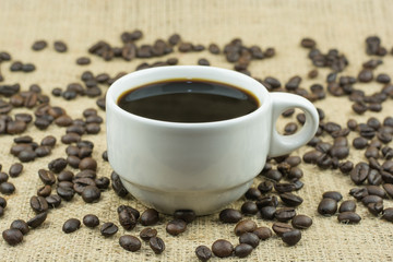 White cup with coffee drink on jute bag background