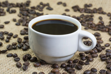 White cup with coffee drink on jute bag background