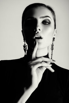beautiful brunette girl with shiny skin, make-up, smoky eyes and pricheskoy.Poziruet in black jacket and red pants in the studio on a white background. Advertising Space