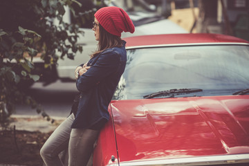 Pretty stylish woman standing by the retro car