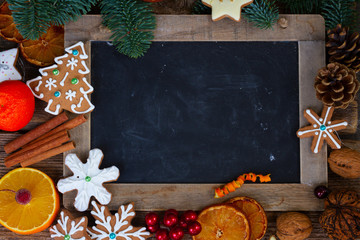 christmas gingerbread cookies with fir tree twigs frame with empty blackboard