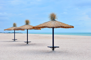 three beach umbrellas on the empty midday beach