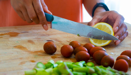 Frau schneidet unterschiedliches Gemüse und Obst auf einem Holzbrett