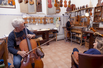 portrait of mature violin maker while testing the violins in his - obrazy, fototapety, plakaty