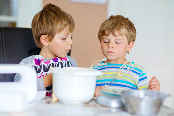 Two kid boys baking cake in domestic kitchen