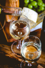 Man is pouring white wine into the glasses