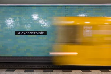 Foto op Plexiglas Berlijn Yellow subway train in Motion. Berlin Alexanderplatz sign visible on the wall of underground station.
