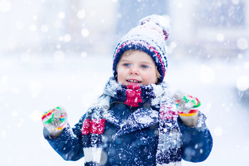 Fototapeta na wymiar Happy kid boy having fun with snow in winter