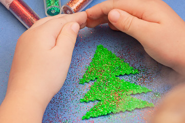children's hands to protect Christmas tree cut from plush sprinkled with glitter