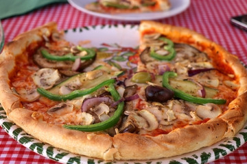 Vegetarian pizza with cheese, tomato sauce, green peppers, mushrooms and onion in a pizzeria. Selective focus. 