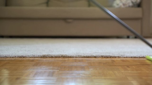 Woman cleaning parquet floors in the living room. Close-up.