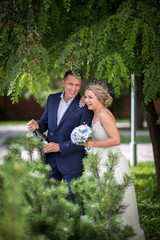 Naklejka premium Bride and groom on the wedding with champagne in greenery