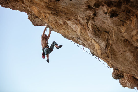 Male rock climber on challenging route on cliff 