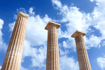 Ancient Greek pillars at the Athens acropolis with blue cloudy sky in the background