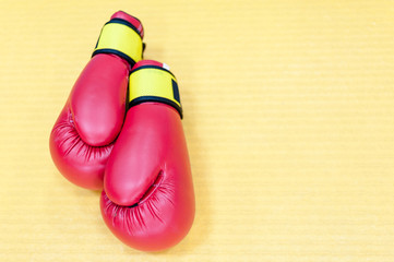 Red boxing gloves lying on yellow mat
