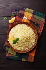 Couscous with mint and lemon in plate on wooden rustic table from above. Copy space for text.