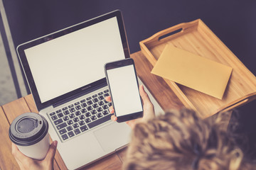 Top view of a girl sitting at a wooden table on which there is a laptop with a blank screen. A girl...